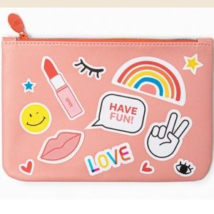Pink makeup bag with multicoloured designs, white stitching and rainbow zipper.